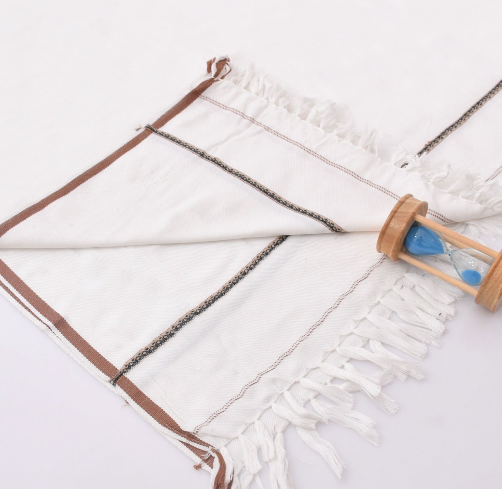 White shawl with brown trim and fringes on a white background