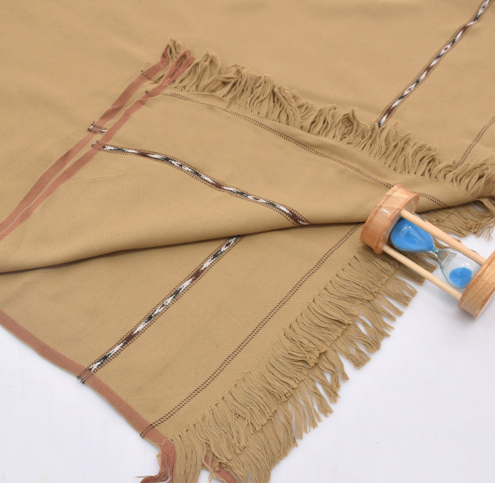 Brown woven Wool fabric shawl with fringes and a wooden sand timer on a white background