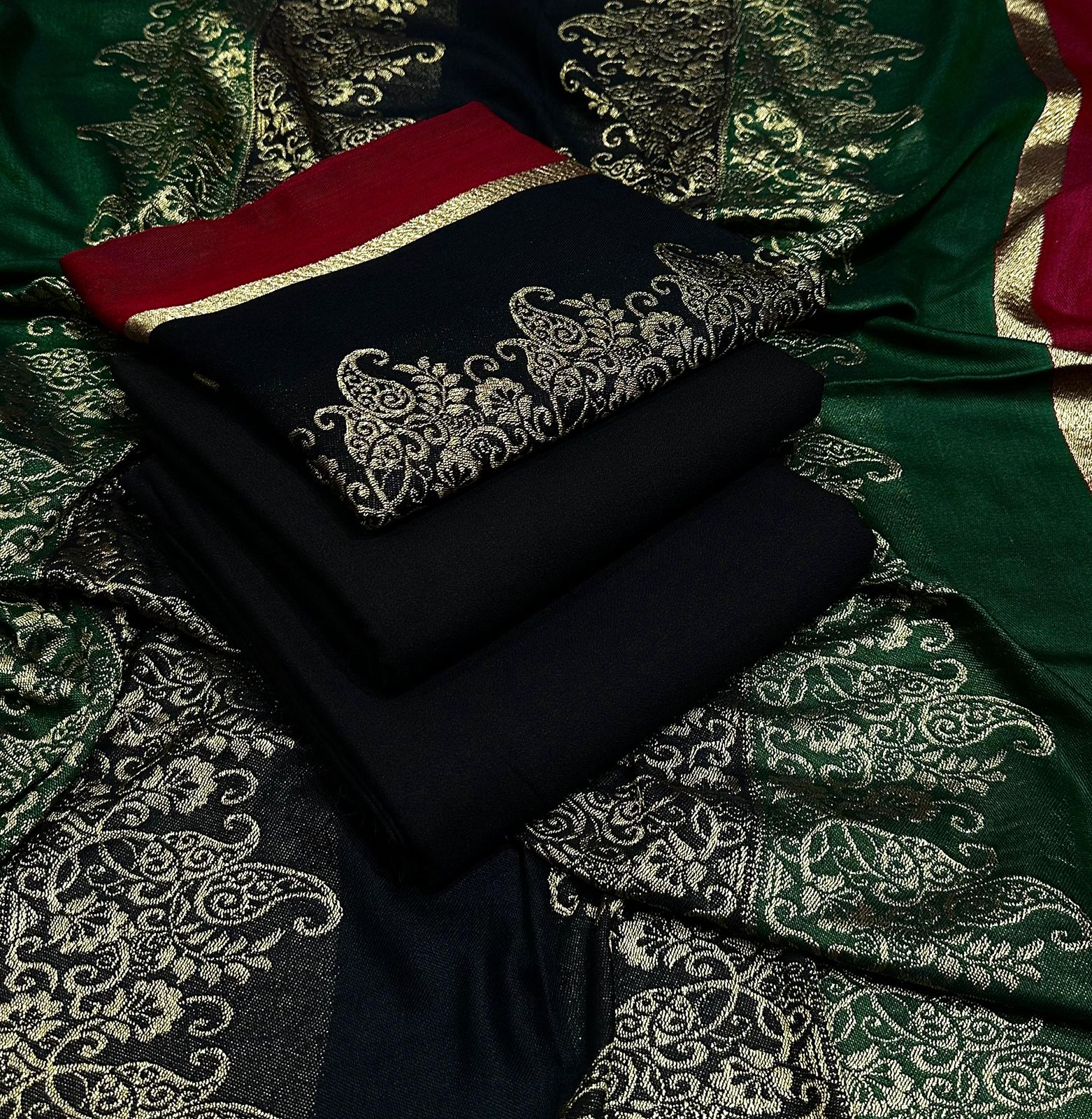 Black fabric with gold embroidery on a green patterned fabric background