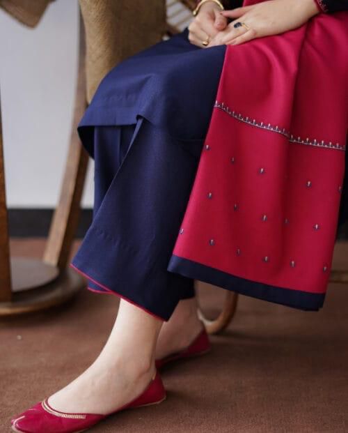 Person wearing a red and navy outfit with a focus on the lower half of the body.Elegant Pakistani winter 3pc suit in linen fabric