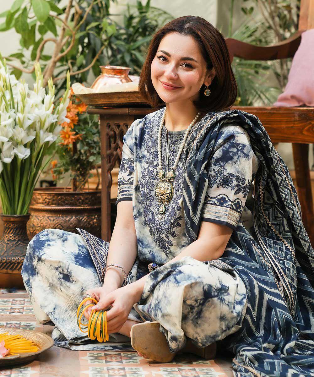 Woman in a patterned outfit sitting on the floor with plants and a table in the background.
Elegant Pakistani winter 3pc suit in linen fabric