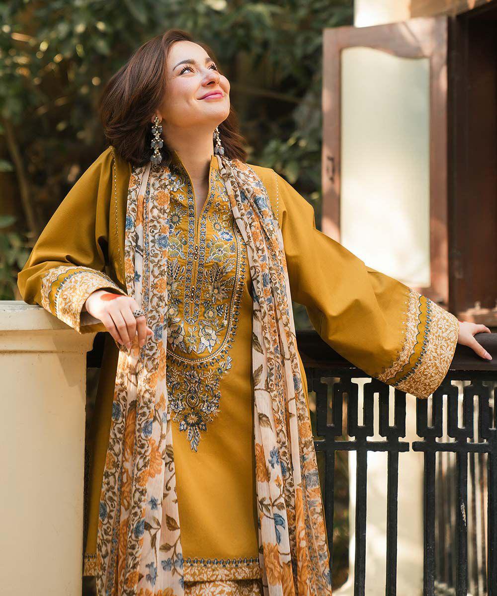 Woman in traditional yellow and patterned outfit with jewelry, standing outdoors.
Elegant Pakistani winter 3pc suit in linen fabric